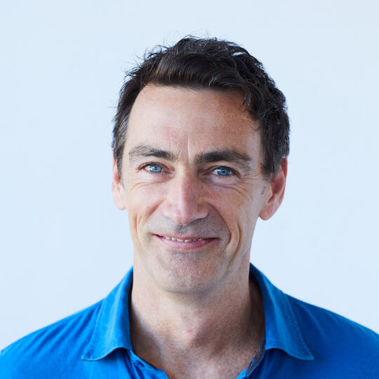 David Newman. Portrait of a smiling man with dark brown hair and a blue shirt.