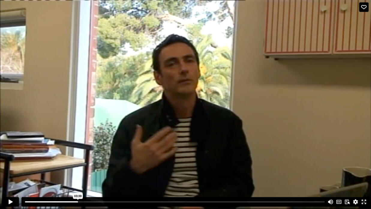 Still from video with man talking and gesticulating
